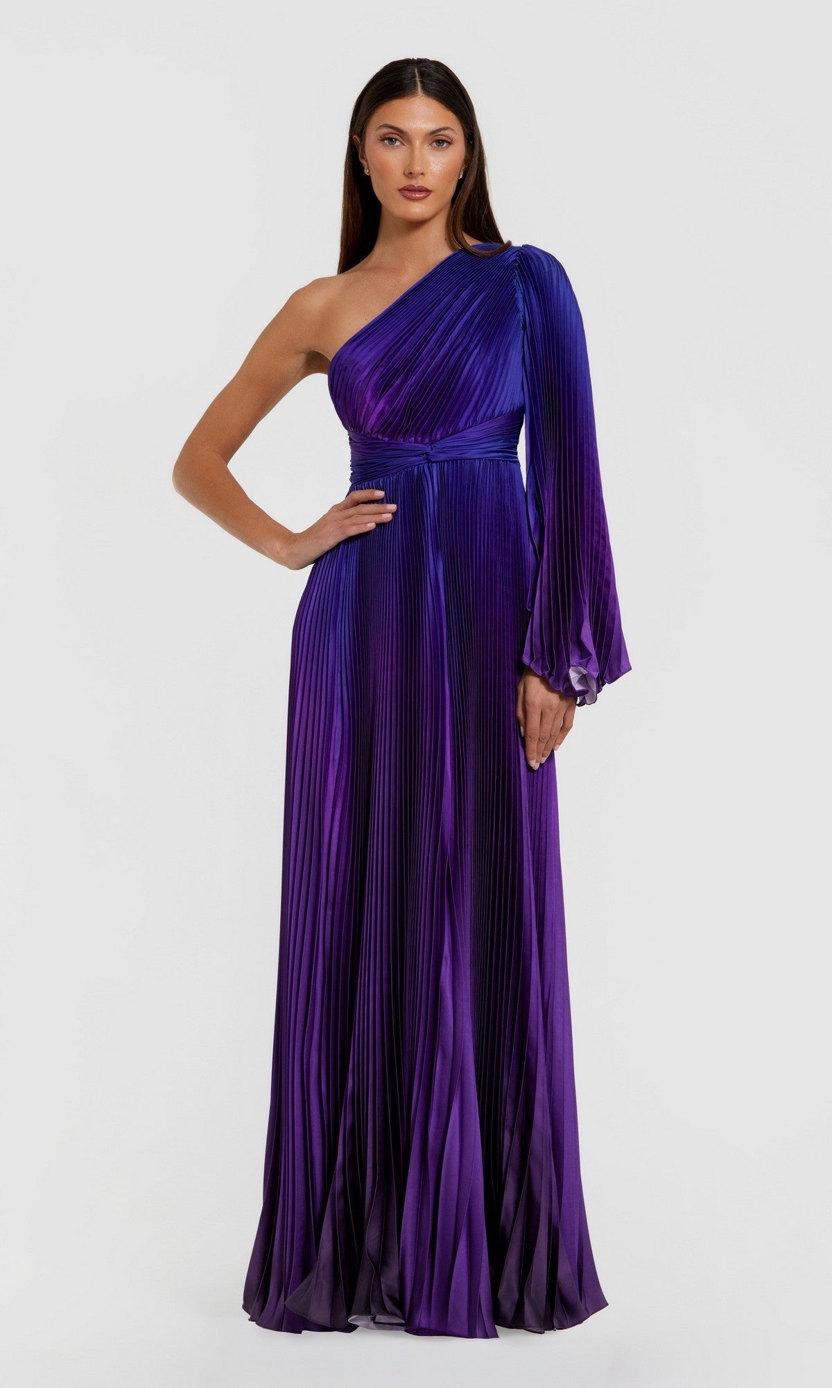 A woman poses gracefully against a plain light background, wearing the Mac Duggal 49903 One-Shoulder Ombre Formal Dress in purple and blue, featuring pleats and a single long sleeve.